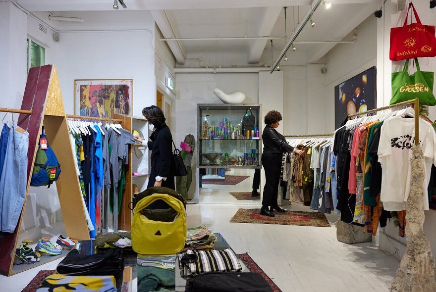 Two people browsing in a streetwear store filled with art.