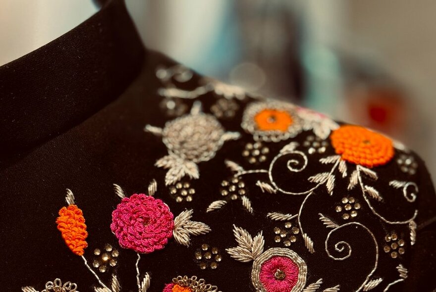 Detail of intricate and colourful embroidery on a black jacket.