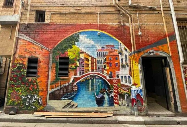 A laneway mural of a boat going down a river