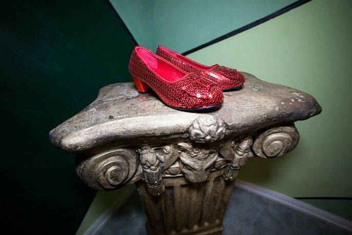 Pair of red shoes on a small table fashioned like a column capital.
