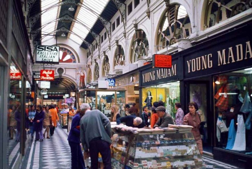 An old photo of people shopping in an arcade.
