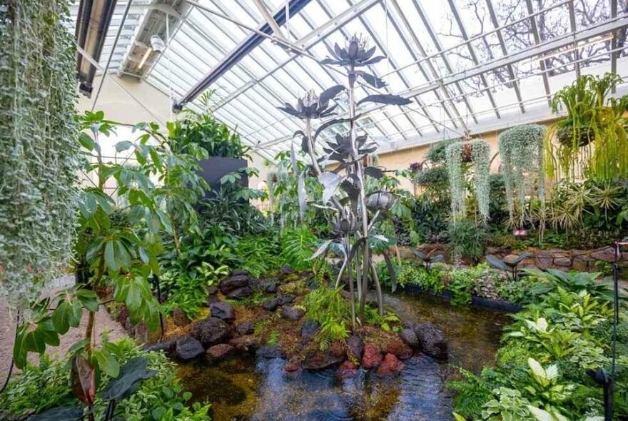 A silver water sculpture in a garden