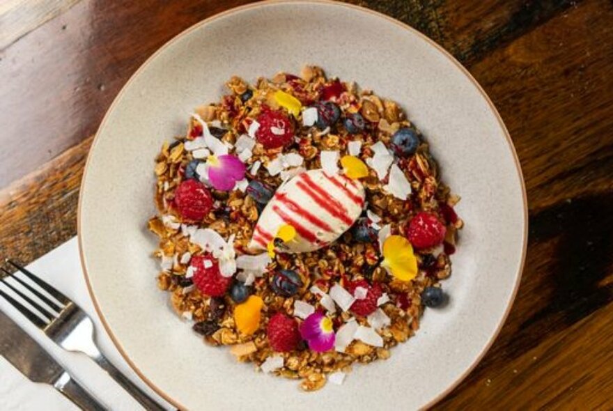 White bowl of muesli with fruit and yoghurt.