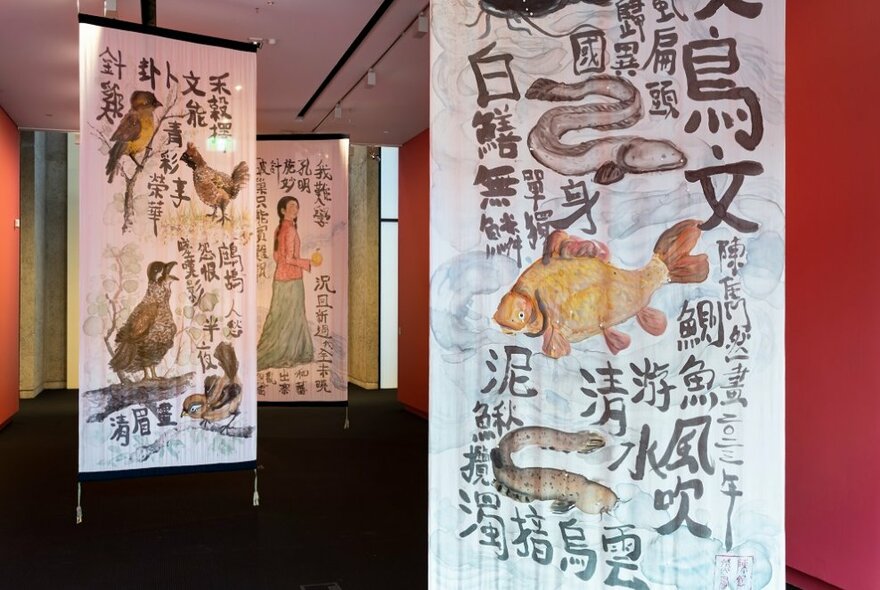 An installation of large silk paintings hanging in a gallery space.