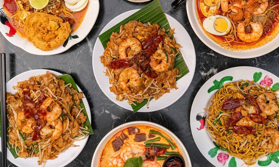 A table set with Malaysian dishes including laksa and char koay teow.