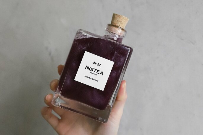 A hand holding a bottle of No 22 INSTEA.