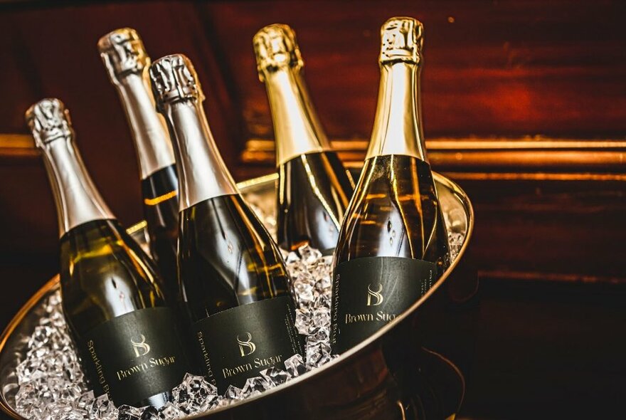 An ice bucket containing five bottles of champagne.