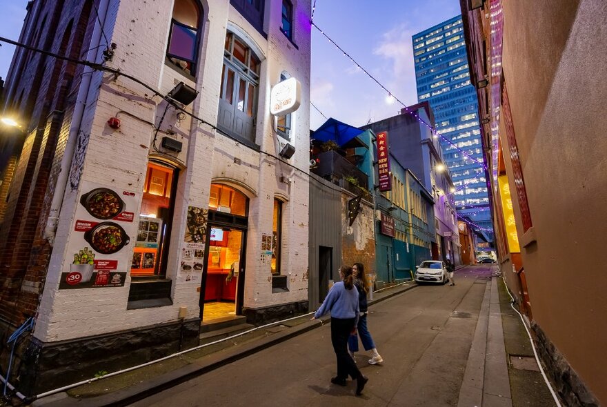 People walking into a building on a laneway with restaurants.