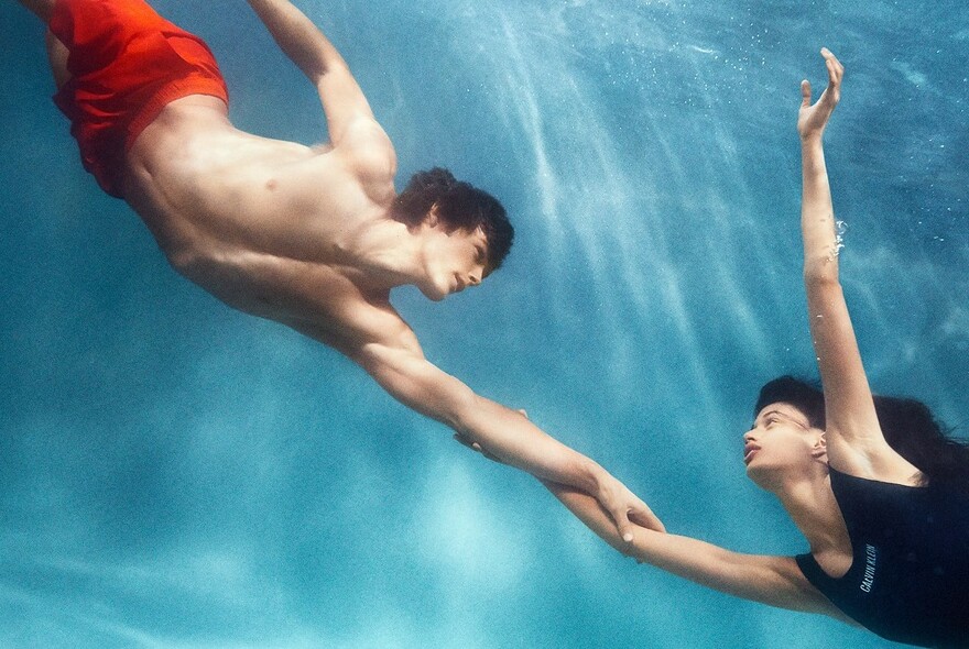 Man and woman underwater and wearing Calvin Klein top and shorts.