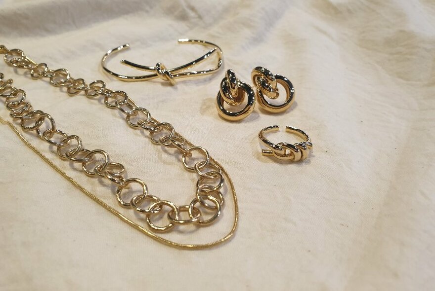 Silver and gold necklaces, earrings and a bracelet displayed on a white background.