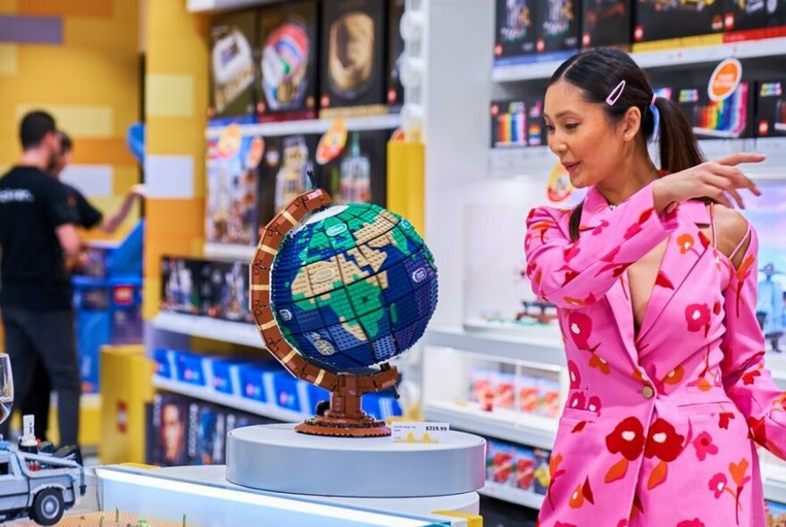 A person revolving a Lego globe of the world in a Lego store.