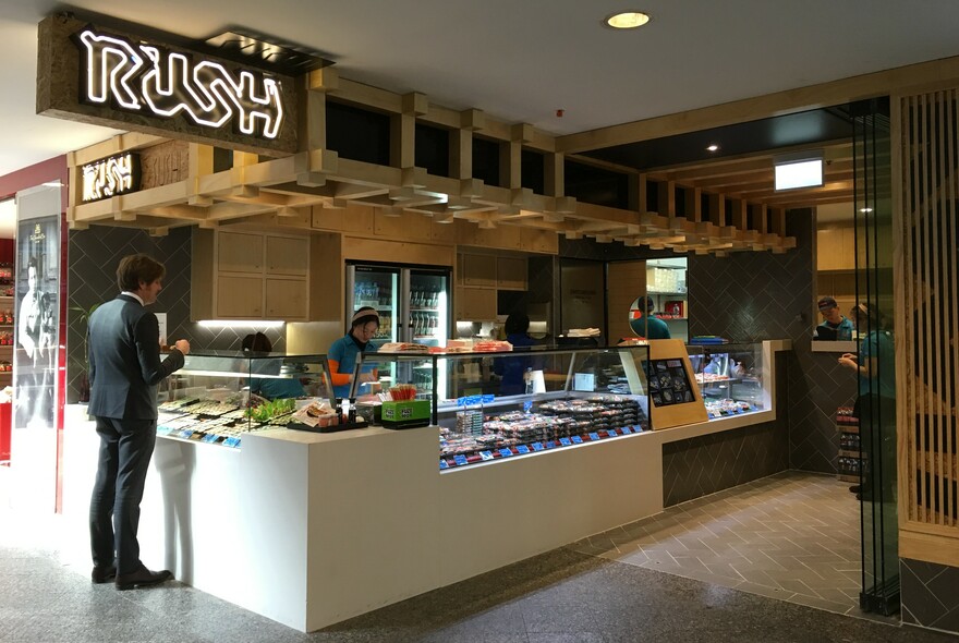 Rush Sushi exterior with signage, counter and customer.