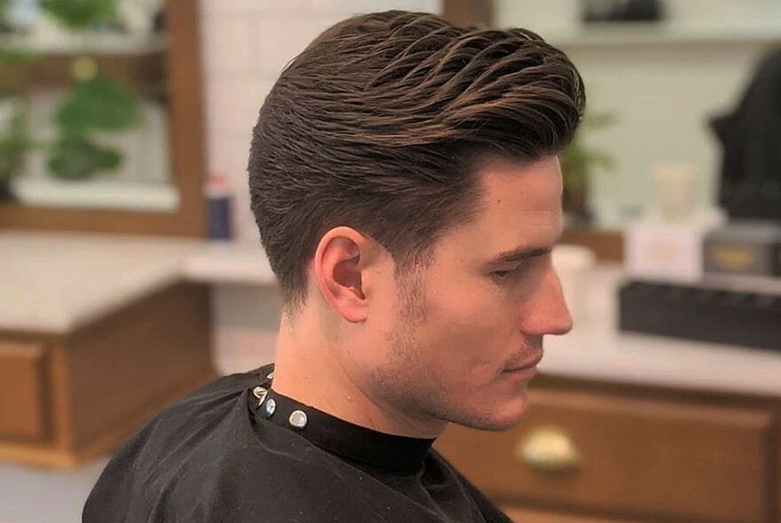 Side view of a man in a salon with newly styled hair.