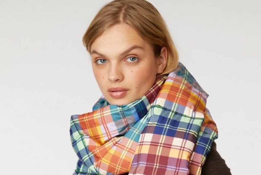 Woman wearing a multi-coloured scarf with a tartan pattern.