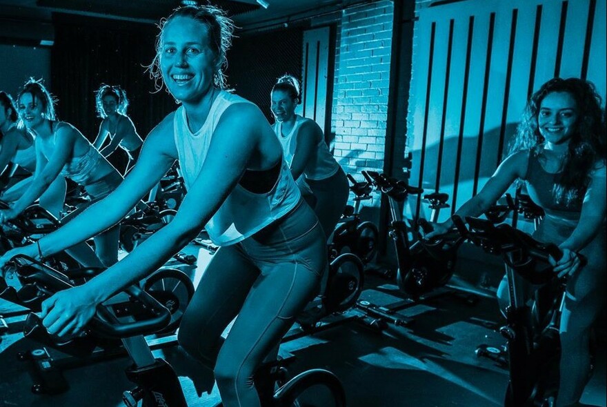 People riding stationary bikes in a exercise spin class.
