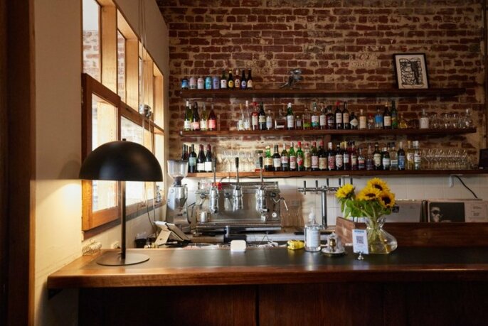 Bar with small standing lamp and sunflowers in vase, brick wall behind.