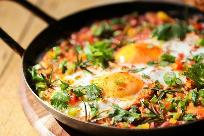 Skillet pan with two fried eggs and other ingredients.