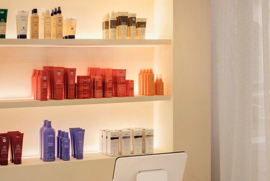Backlit shelves holding rows of Aveda products.