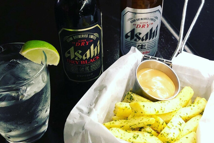 A gin cocktail and Asahi beers with a box of chips with mayo.