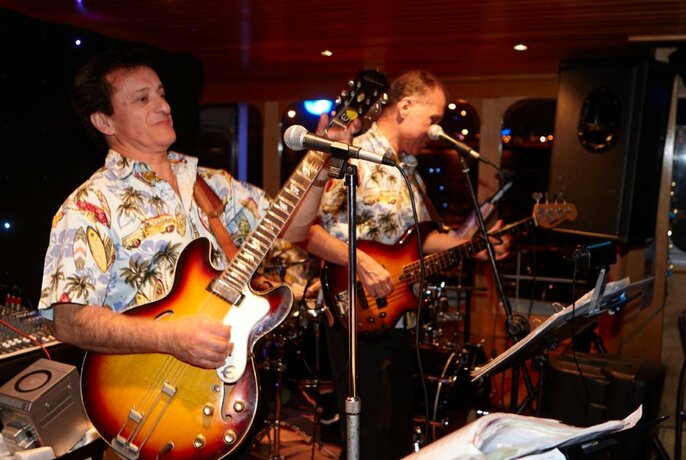 Musicians playing guitars in a band performing on board a boat.