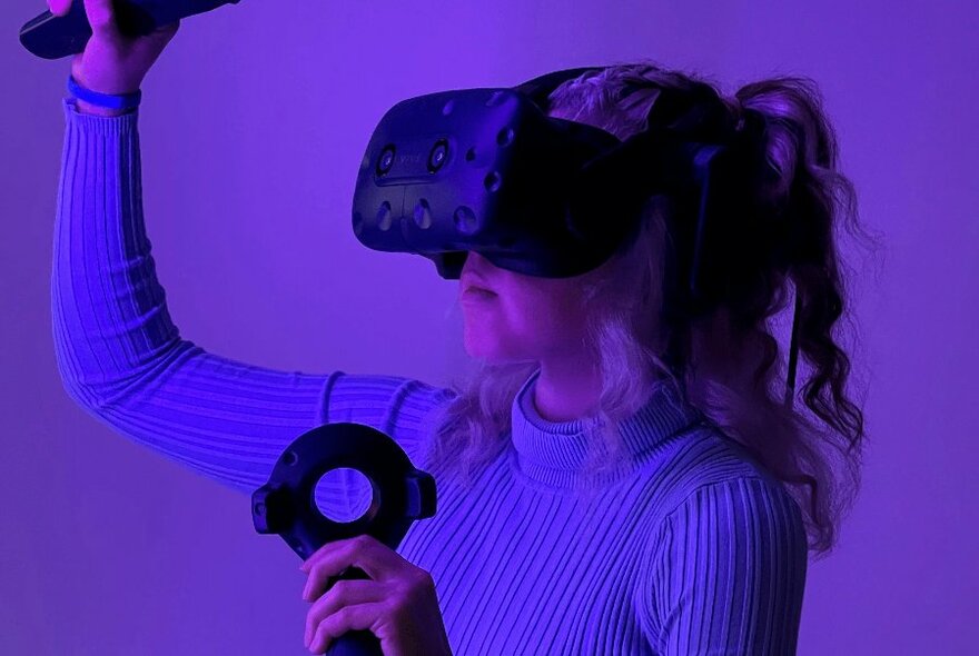Someone wearing VR goggles in a purple room. 