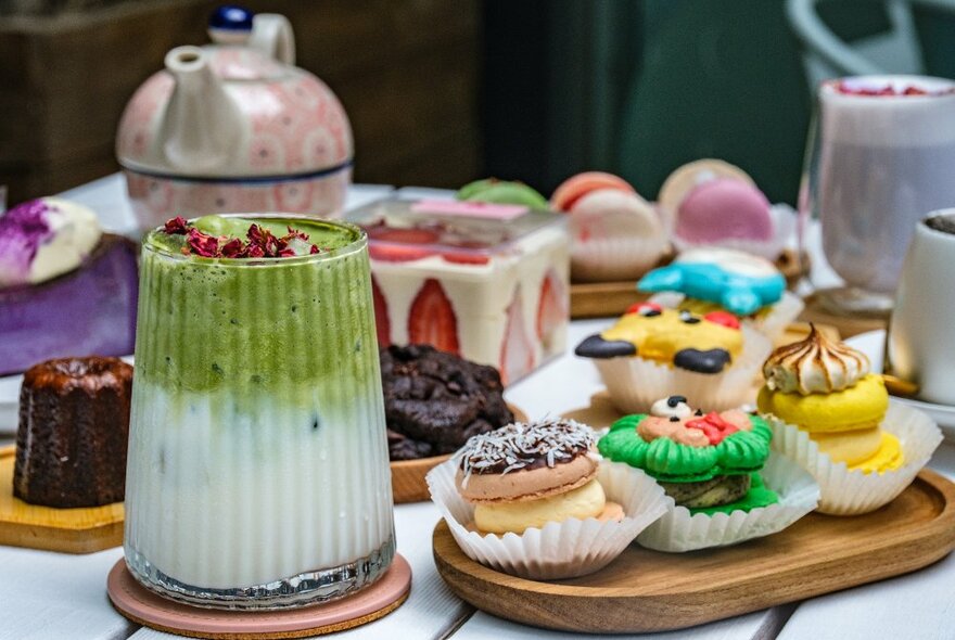 A table with macarons, cakes and a matcha latte on it