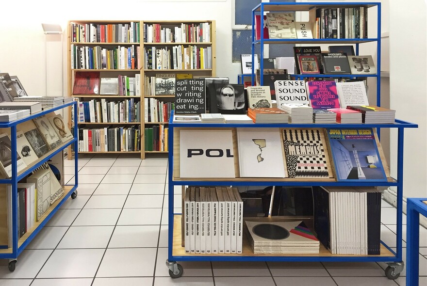 Interior of shop showing shelves and display tables of large art books.
