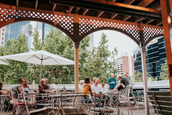 Customers seated at tables under awnings on the deck.