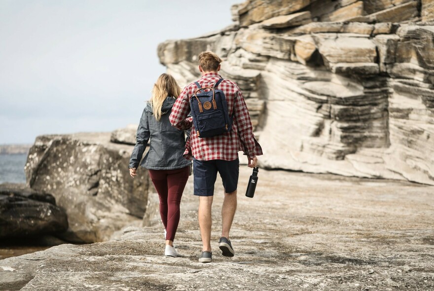 Two people walking in the mountains, one with a  with Fjallraven backpack.