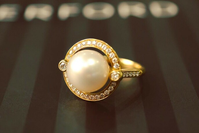 Gold ring with a single pearl surrounded by diamonds