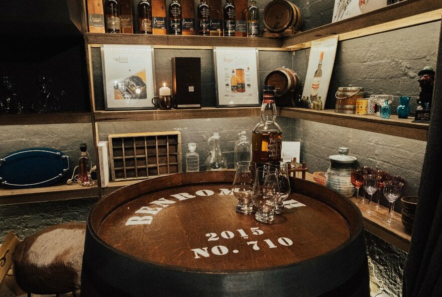 A bottle of whiskey on top of a barrel in a bar's barrel room.