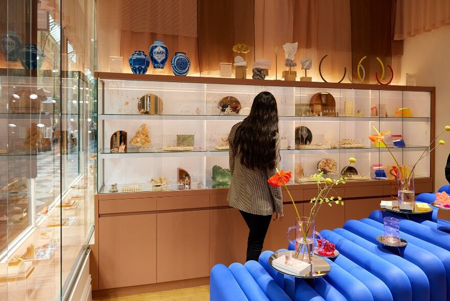 A woman browsing in a modern jewellery shop with sculptures and flower displays. 