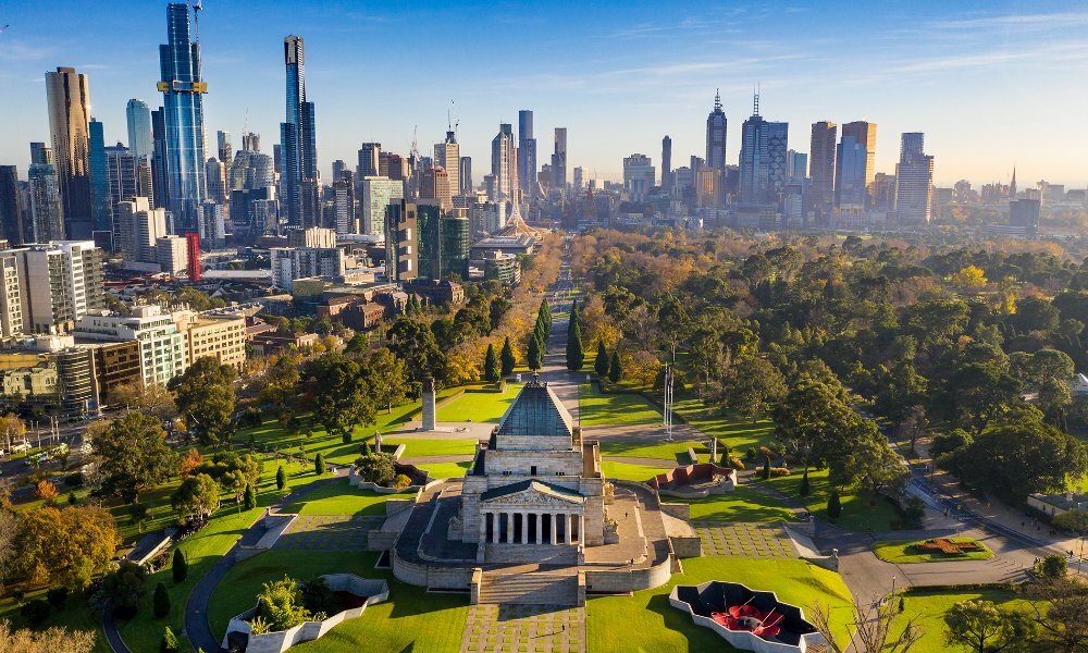 An aerial shot of the Shrine of Remembrance on a sunny day with the city and parklands in the background. 