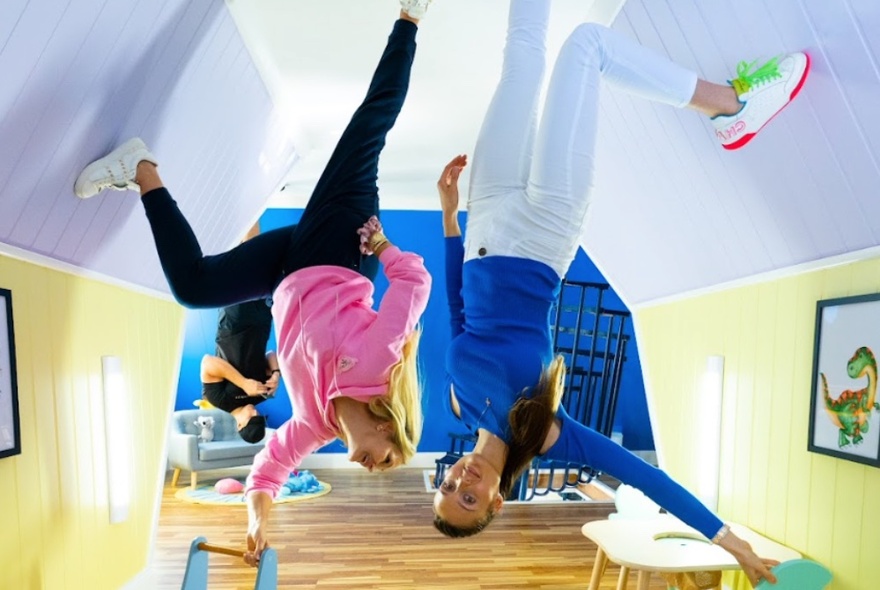 Two people standing on the 'ceiling' of an inverted kids play room.