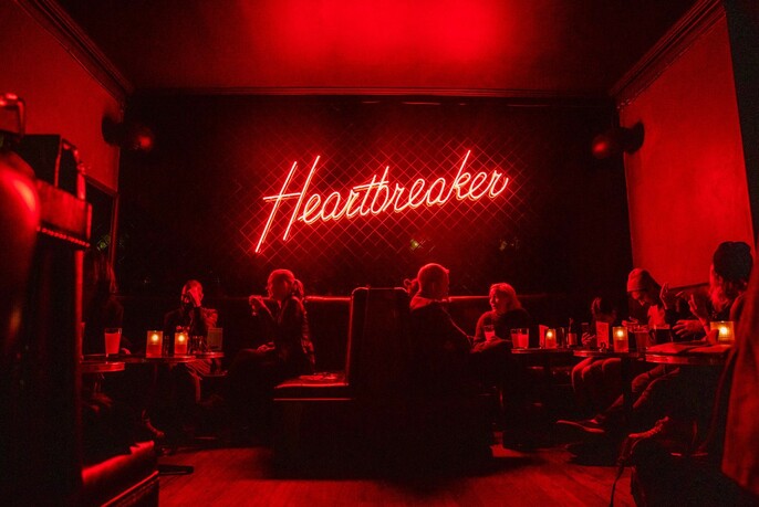 The red lit interior of Heartbreaker, with a red neon sign on the wall. 
