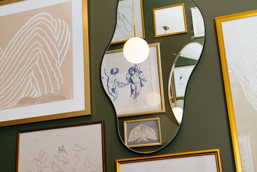 Mirror and artworks decorating a grey wall.