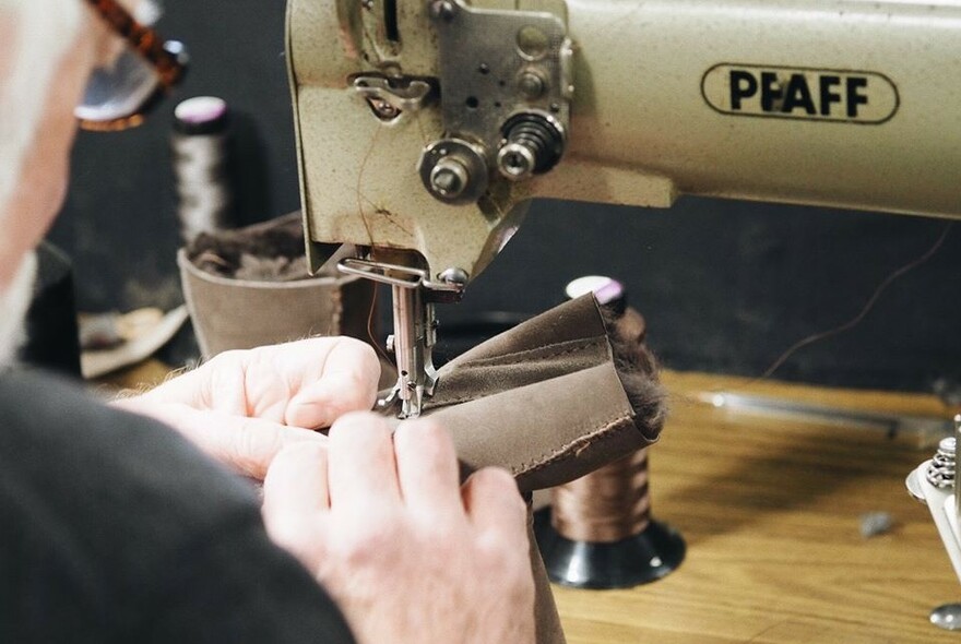 Person using a sewing machine to make a sheepskin boot.