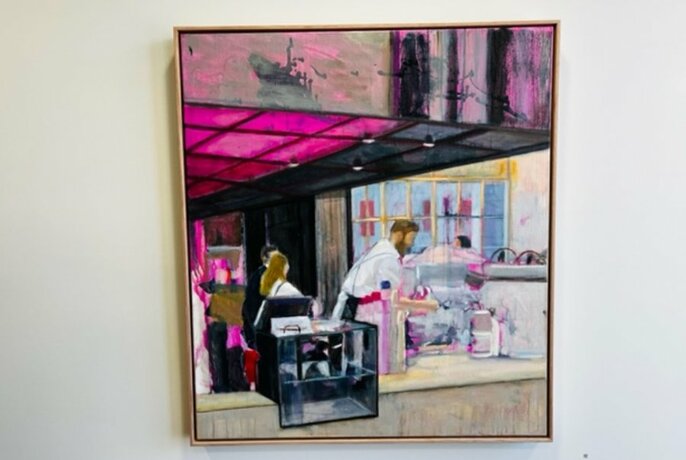 Painting of a cafe scene hanging on a white wall.
