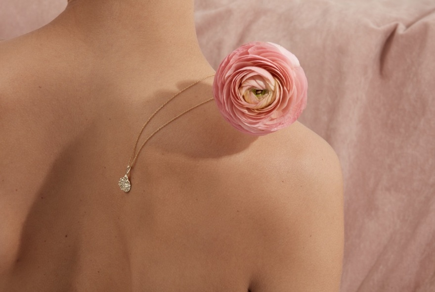 Flower and pendant over naked shoulder.