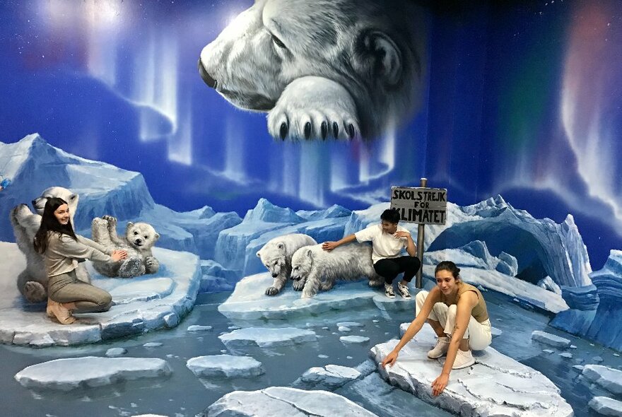 People posing and fooling around against a fantasy Arctic backdrop and floor with polar bears depicted.