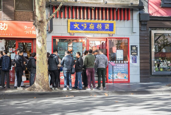 People queing in the street outside David's Spicy Pot restaurant.