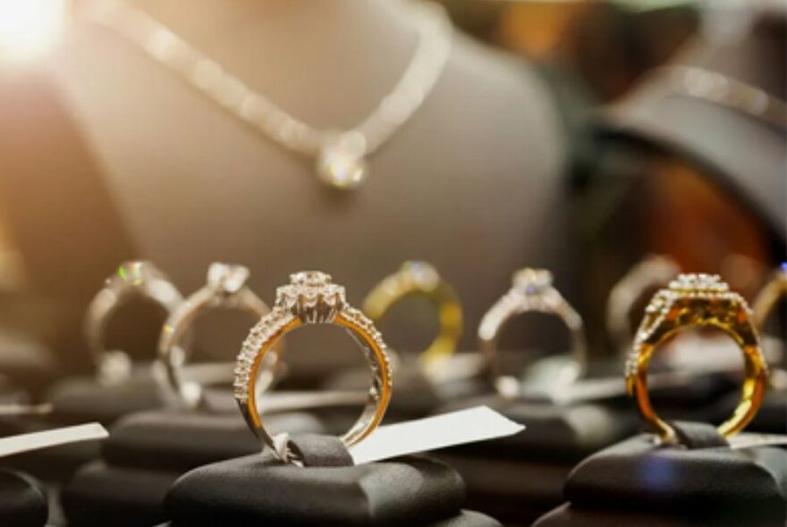 A tray of diamond rings, with diamond necklaces on stands in the background.