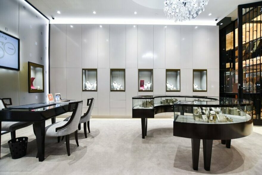 The carpeted interior showroom of Franco Jewellers with glass display cabinets, and a desk with two club chairs for buyers to sit at.