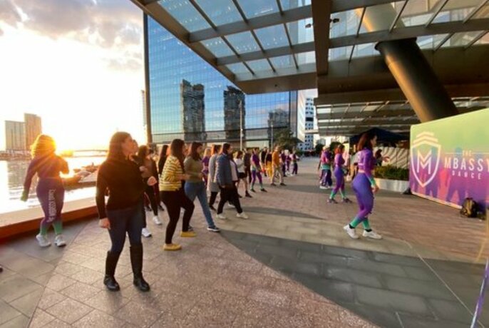 Lines of people dancing in unison in an outdoor setting at sunset.