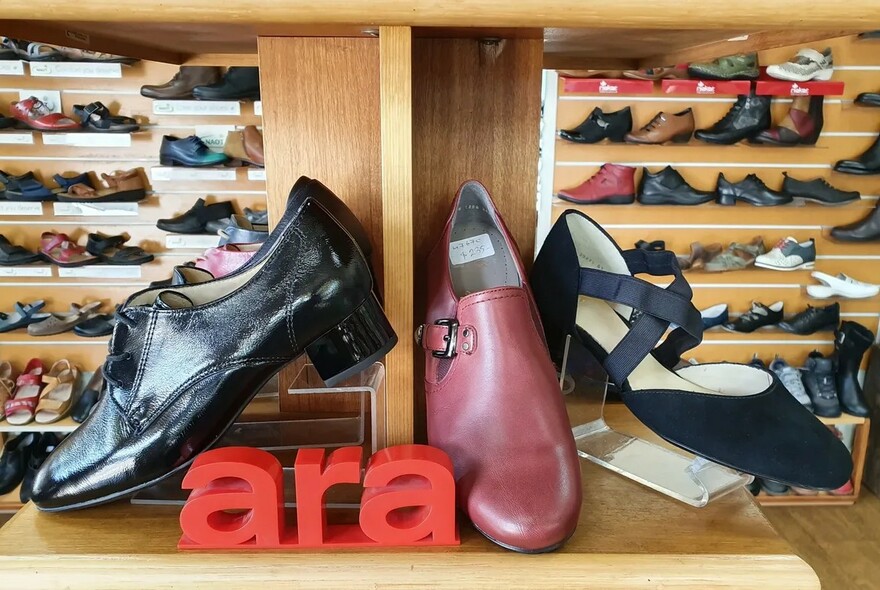 Ara shoe display with styles of men and ladies and rows of shoes on wooden shelves in the background.