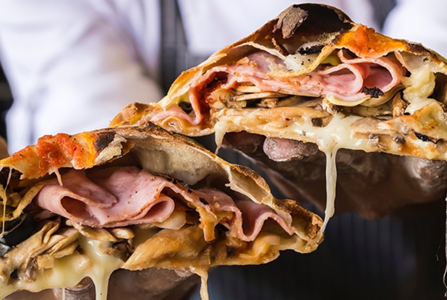A cross-section of a toasted pocket with ham, mushrooms and oozing cheese.