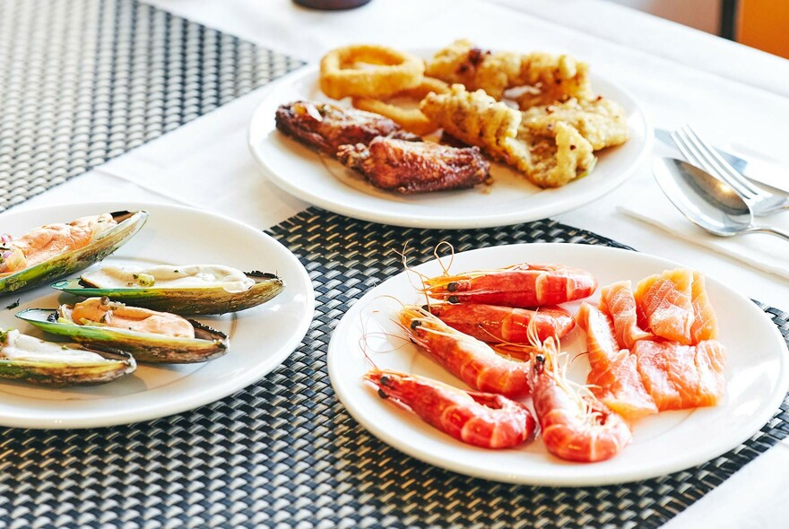 Buffet plates on a table with prawns, oysters and crumbed seafood.