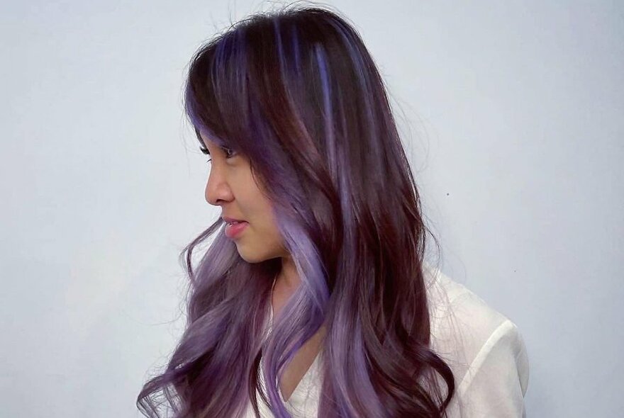 Woman with long purple hair, viewed from the side.