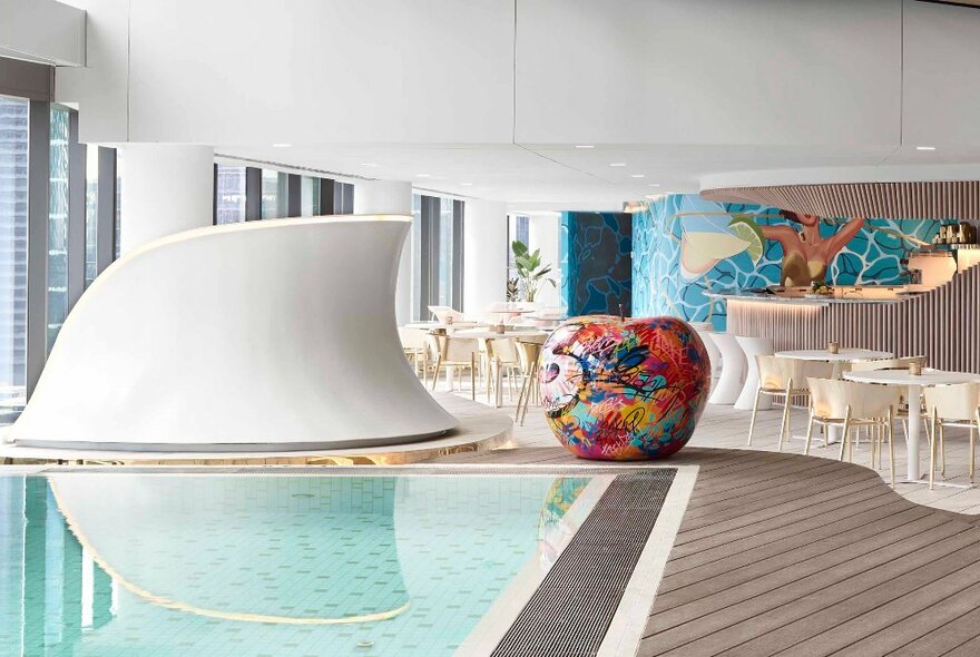 Indoor pool at an up-market hotel with artwork, sculptures and chairs and tables. 