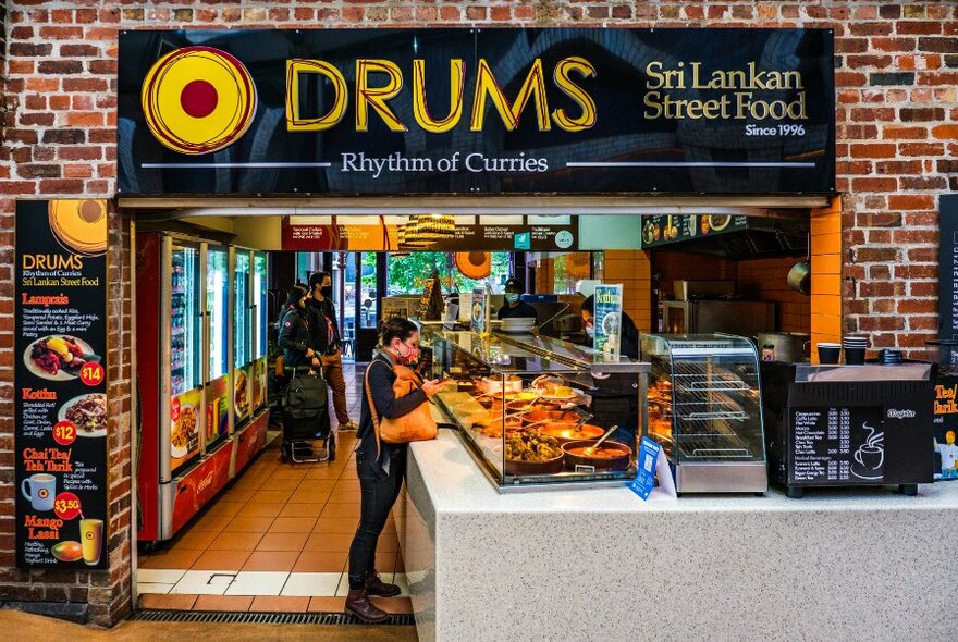 People at the counter of a Sri Lankan street food shop called Drums.
